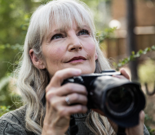 Older woman taking pictures in the woods