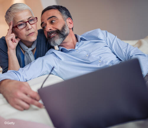 Adult man and woman looking at a laptop together