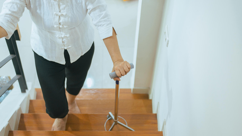 Person walking up stairs with cane