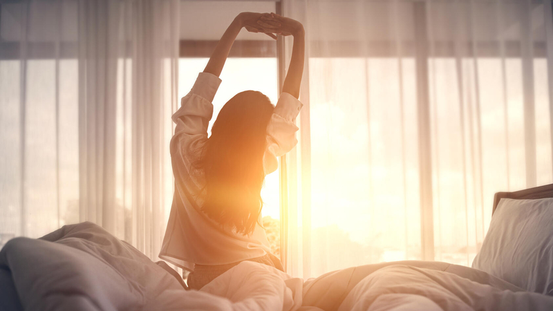 Woman stretching as she gets out of bed