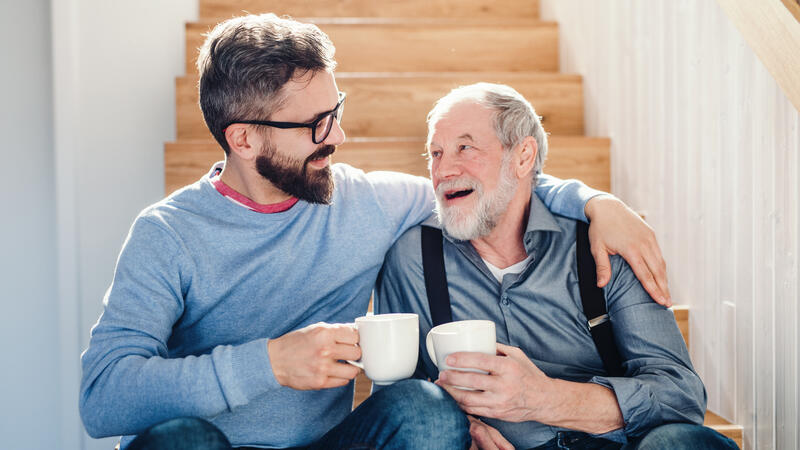 Elderly man and adult son smiling