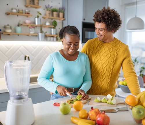 Man and woman preparing food in kitchen.