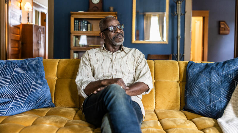 Man sitting on yellow sofa looking off camera