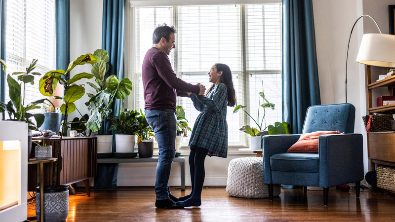 Father dancing with daughter in livingroom