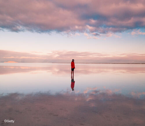 Person standing on wet reflective sand