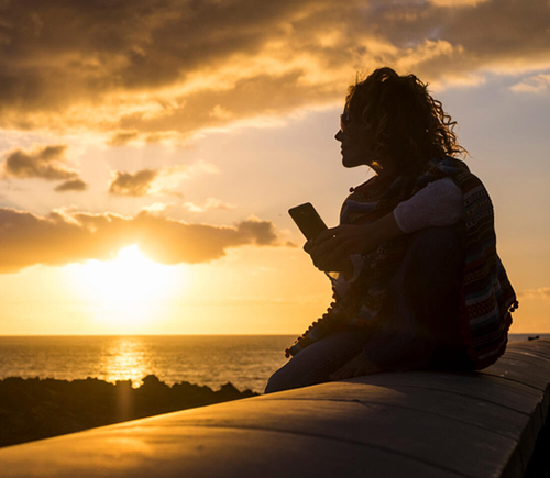 Person sitting on a wall at sunset