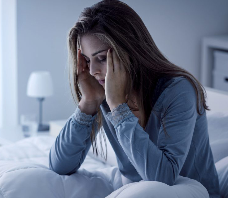 Woman rubbing temples in bed