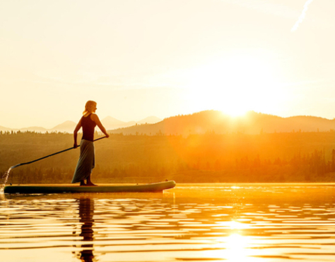 Woman on stand up paddle board in sunrise