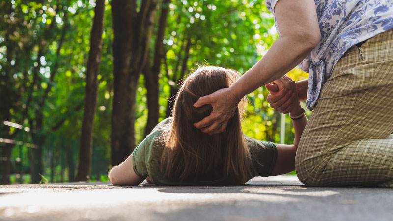 Woman laying on pavement after a fall