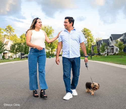 Man and woman walking dog in neighborhood
