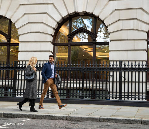 Man and woman walking on sidewalk.