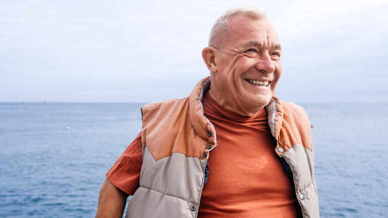 Man in orange standing in front of the sea