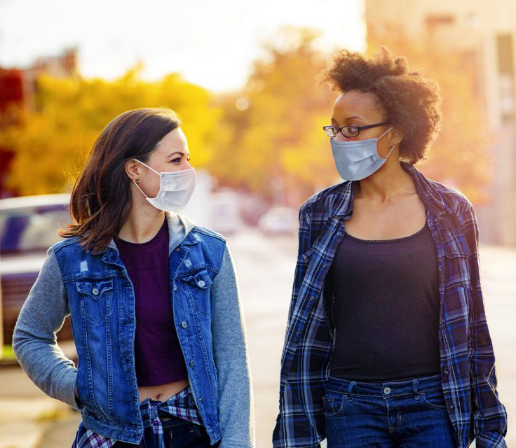 Two masked people walking together outside